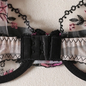 Detail of floral embroidery on black mesh lingerie featuring a three-row hook and eye closure