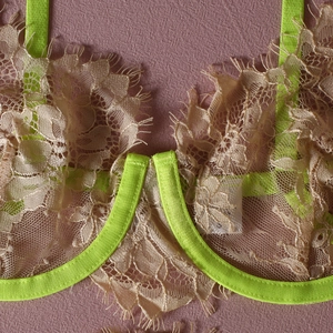 Macro view of champagne floral lace bra with neon green trim and eyelash lace detail