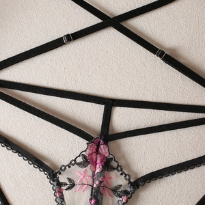 Detail of floral embroidery and adjustable straps on these sexy black mesh thongs