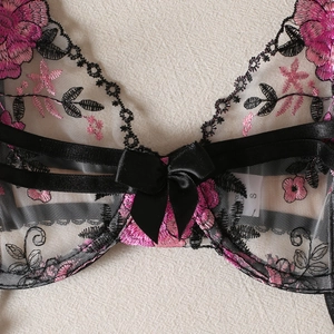 Black lace lingerie set featuring pink floral embroidery and a satin bow detail