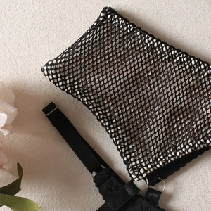 Détail de la lingerie en maille noire avec anneaux métalliques et bretelles réglables