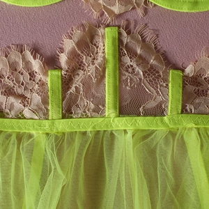 Macro detail of neon green lace and pink embroidery on underwired lingerie set