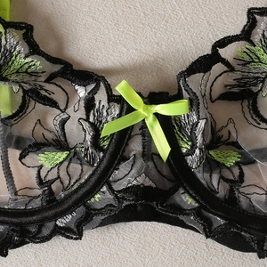 Vue détaillée de la broderie florale sur tulle transparent avec nœud en satin néon