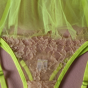 Detail of neon green lace lingerie with delicate mesh texture and metal strap sliders