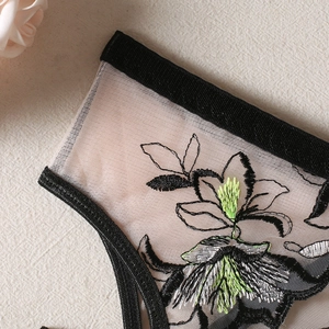Détail macro de broderie florale sur lingerie en tulle transparent avec fils vert néon