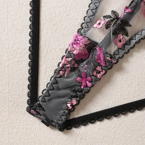 Macro shot of pink floral embroidery on black mesh lace with delicate scalloped edges