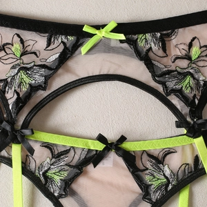 Détail de broderie florale sur lingerie en tulle avec bretelles vert néon et petit nœud