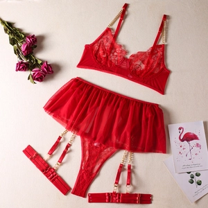 Flat lay of red floral lace lingerie set with gold metal chain straps and garter skirt
