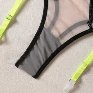 Détail de lingerie en maille noire avec bretelles vert néon et attaches porte-jarretelles
