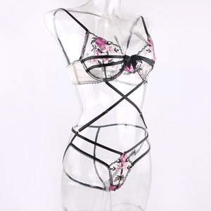 Detail of floral embroidery and strappy lace-up structure on a black mesh lingerie set