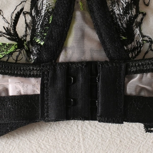 Détail de l'agrafe dorsale en résille noire avec broderies florales colorées et dentelle