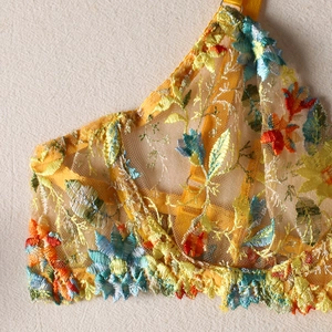 Close-up of intricate multi-color floral embroidery on sheer yellow lace mesh fabric