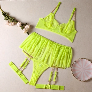 Flat lay of neon yellow lace lingerie set with gold chains and sheer mesh skirt