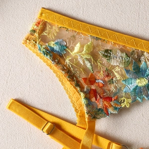 Close-up of yellow mesh lingerie featuring colorful floral embroidery and metal buckles