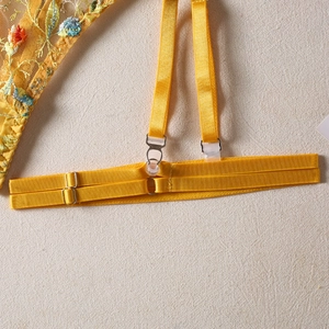 Close-up of yellow floral lace embroidery and satin straps on three-piece lingerie set