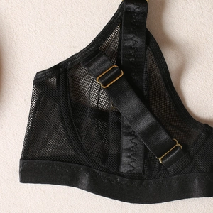 Detail of black mesh bra with satin binding and adjustable gold hardware buckles