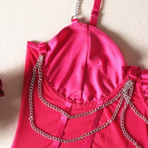 Détail du haut corset rose avec chaînes métalliques et texture de tissu en maille