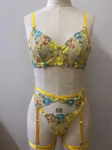 Close-up of yellow sheer mesh lingerie set with vibrant floral embroidery and garter belt
