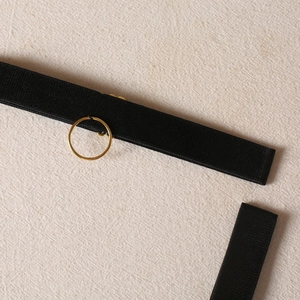 Detail of black ribbed fabric strap and polished gold metal ring on a sexy lingerie set
