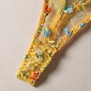 Gros plan du string en mesh jaune avec des détails de broderie florale multicolore