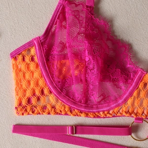 Macro detail of vibrant lace bra featuring orange mesh and magenta embroidery with steel wire