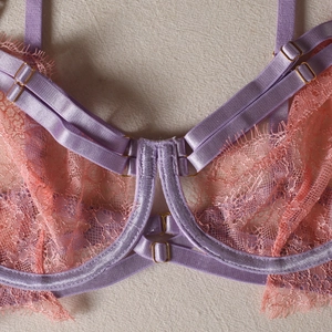 Détail de dentelle florale rose et bretelles en satin violet avec boucles en métal doré