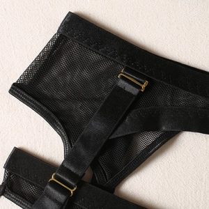 Detail of black mesh garter belt with golden metal buckles and elastic straps