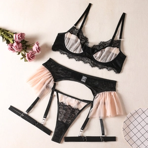 Flat lay of a 3-piece black lace lingerie set with pink mesh ruffles and floral accents