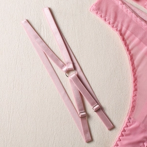 Close-up of pink mesh lingerie detailing metal buckles and elastic adjustable straps