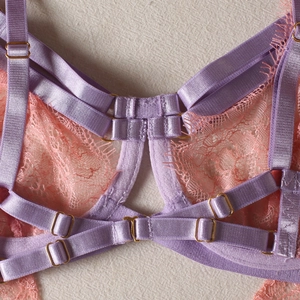 Détail de soutien-gorge en dentelle lilas avec bretelles corail et boucles en métal doré