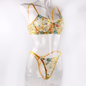 Détail de lingerie en maille jaune avec broderies florales colorées et bords en satin