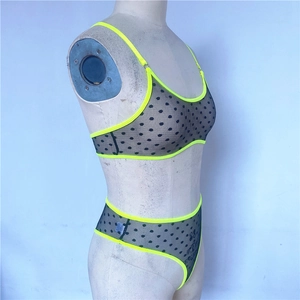 Macro detail of fluorescent green trim on black polka dot mesh lingerie two-piece set