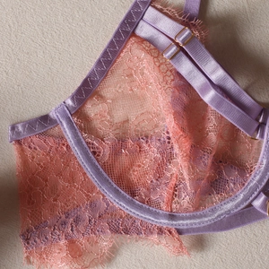 Détail de la dentelle florale rose avec garniture en satin violet clair et boucle dorée