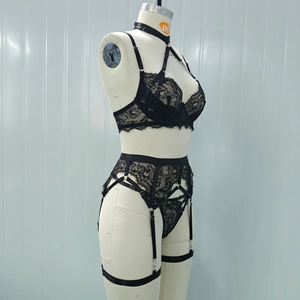 Detail of black lace lingerie set with harness straps and leg rings on a mannequin