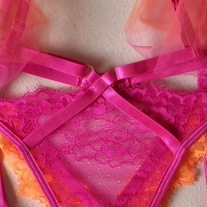Detailed close-up of neon pink and orange lace lingerie with gold ring and mesh texture