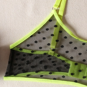 Macro detail of neon green straps and black polka dot mesh fabric on the bra set