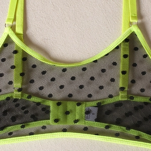 Detailed macro view of neon green mesh bra with black polka dots and back hook closure