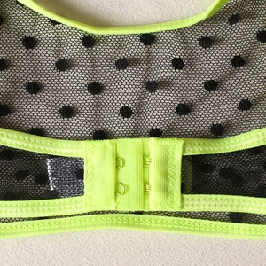 Detail of the neon green hook-and-eye back closure on the polka dot mesh bra