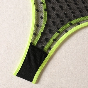 Close-up detail of black polka dot mesh fabric with neon yellow elastic trim stitching