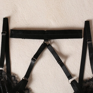 Detail of black lace lingerie showing adjustable straps and silver metal hardware rings