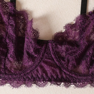 Close-up of deep purple eyelash lace with intricate floral patterns and black straps