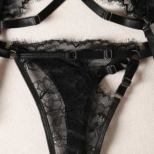Close-up of black floral lace texture with adjustable straps and silver metal buckles