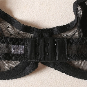 Close-up of black polka dot mesh bra with double-row hook and eye back closure