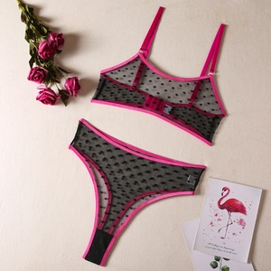 Detail of sheer black polka dot mesh lingerie set with vibrant fuchsia ribbon trim