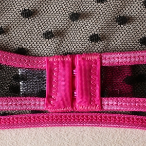 Macro view of bright pink elastic straps and black polka dot mesh with back hook closure