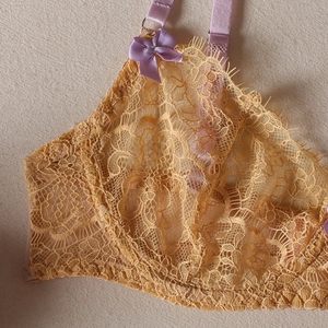 Détail du soutien-gorge en dentelle jaune avec broderies mauves et nœuds délicats