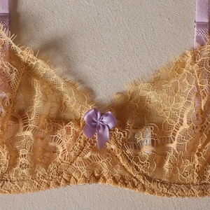 Détail du soutien-gorge en dentelle jaune avec bretelles violettes et nœud en satin