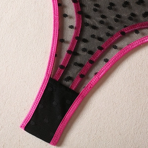 Detailed macro view of black polka dot mesh fabric with neon pink satin stitched edging