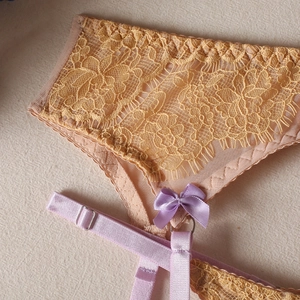 Détail de culotte en dentelle florale jaune avec nœud en satin violet et porte-jarretelles