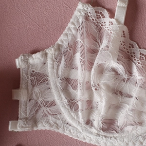 Close-up of white floral lace lingerie with translucent mesh and side buckle closure